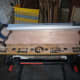 Clamping the dowelling jig into place on the edge of the plank