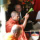 Monks bless the guests by sprinkling everyone with flowered water.