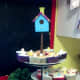 Painted birdhouse surrounded by bird nest cupcakes.