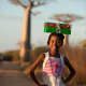 A girl balancing her shoebox on her head in Madagascar.