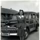 Woman standing in front of 1942 Ford Woodie during World War II.