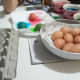 Here, some coloured eggs are drying on a paper towel while some dry eggs have already been placed in the carton. 