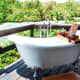 One of the free standing open air bathtubs on a wooden deck of one of the rooms