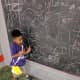 Juju shows off his doodle at the chalkboard.
