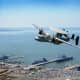 An E-2D Hawkeye flies over Naval Base Norfolk in Norfolk, VA