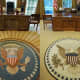 New York Magazine referred to the Obama Oval Office rug (right) as the "less-optimistic rug" as compared to the rug from George W. Bush's Oval Office (left) with its radiant lines that move out from the presidential seal.