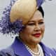 Queen SiriKit (Queen of Thailand) wearing a multi-strand pearl necklace with a white hat and purple plumes and a purple suit