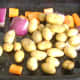 Prepared vegetables are oiled and seasoned in the base of the roasting tray