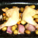 Roasted chicken legs and vegetables are removed from the oven