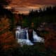 A slow shutter speed (and a tripod) is used to capture a waterfall at sunset, surrounded by fantastic fall foliage.