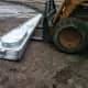 A stack of roof sheets is ready to be used, kept conveniently off the wet ground by the loader forks. 