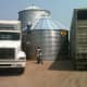 2 trucks are used as a handy way to block in an almost-finished bin until a crane can be brought in to finish the last ring, and lift the bin to a hopper. Finished grain bins shelter the bin from the windward side.
