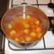Potatoes, carrots and beef stock are added to pot and seasoned