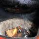 Adding wood chips to coals.