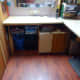Original storage under the side desk before the office makeover. Redundant Ikea computer desk repurposed as shelving and structural support for the side desktop, with waste bins below; and paper storage cabinet on the right