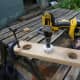 Cutting access points, with a large hole saw, in the two large pieces of recycled wood being used to make teh cable management trough