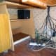 The old Ikea desk relocated to the corner beneath the main desk, and base speaker wired up on the top shelf