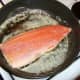 The trout fillet is laid in a hot pan with the skin side down.