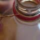 Close-up of insertion of the wire hanger under the round plastic ring on the pop bottle mouth.