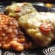 Mashed potato on toast topped with grated cheddar cheese and tomato and served with baked beans.