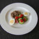 Salad and egg are plated with a thick slice of jellied ox tongue