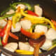 Peppers are added to and stir fried with chicken