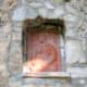 A terra cotta plaque set within a recessed niche of limestone cobbles.
