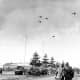 Photo taken by a U.S. Army Signal Corps photographer on December 26, 1944, in Bastogne, Belgium as troops of the 101st Airborne Division watch C-47s drop supplies.