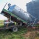 A flatbed truck with a hoist is used to set the bin onto the barrels.
