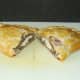 Pasty is carefully halved on chopping board