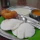 The idli is in white. The brown colored round dish is vada which is also many times served with idli sambhar if asked for it. Vada is made by frying a batter of dal, lentil, gram flour or potato. They have a shape similar to a doughnut.