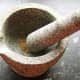 Toasted cumin seeds are ground in a pestle and mortar