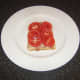 Tomato slices are laid on top of bacon