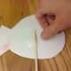 Attach a popsicle stick to the back of the fish with tape.