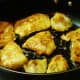 Photo of sautéing the lightly battered fillets of fish in a non-stick skillet on top of the stove.