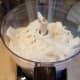 Then I pull my coconut oil out of the freezer and break it all into small pieces. I add that to my processor and process that in as well.