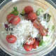 Salad leaves, grated turnip and tomato halves are seasoned and combined