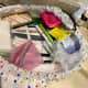 Using a pink cotton swab container to hold tweezers, small nail clippers, small scissors and spoolie.