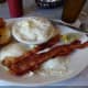Eggs over medium with bacon, biscuits and grits.