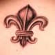 Copper-colored fleur-de-lis tattoo