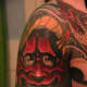 A red hannya tattoo with a snake between her teeth.