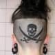 a skull and swords tattooed on the back of someone's head