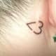 a small heart tattooed behind a person's ear