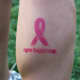 Pink ribbon tattoo above "New Balance" text.