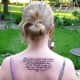 Tattoo of a poem and design elements on upper back.