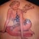 A pinup girl wearing an American flag bikini with the words "Miss Behavin" inscribed above.