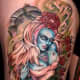 This pinup girl tattoo has some unique features, such as blue skin and climbing roses.