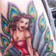 A pinup girl sitting on a cupcake with peacock feathers in the background.