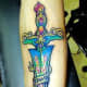 A colorful sword tattoo with text.