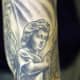A cherub tattoo that inked in mostly black and grey.